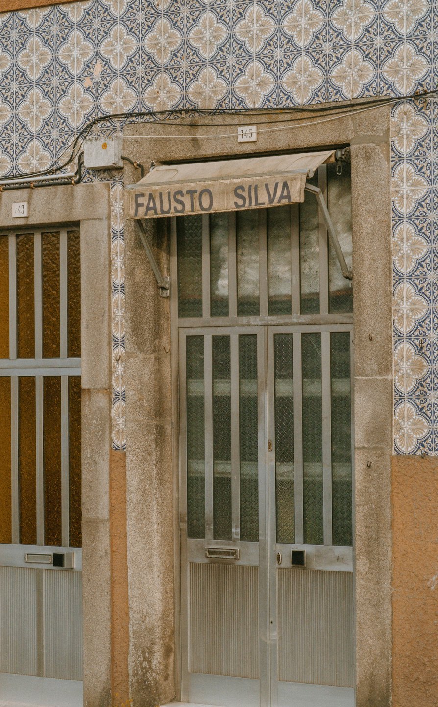 Ornate tiled building facade with a Fausto Silva metal door.
