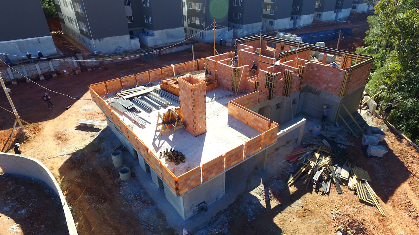 Construction workers building a structure on a dirt site.