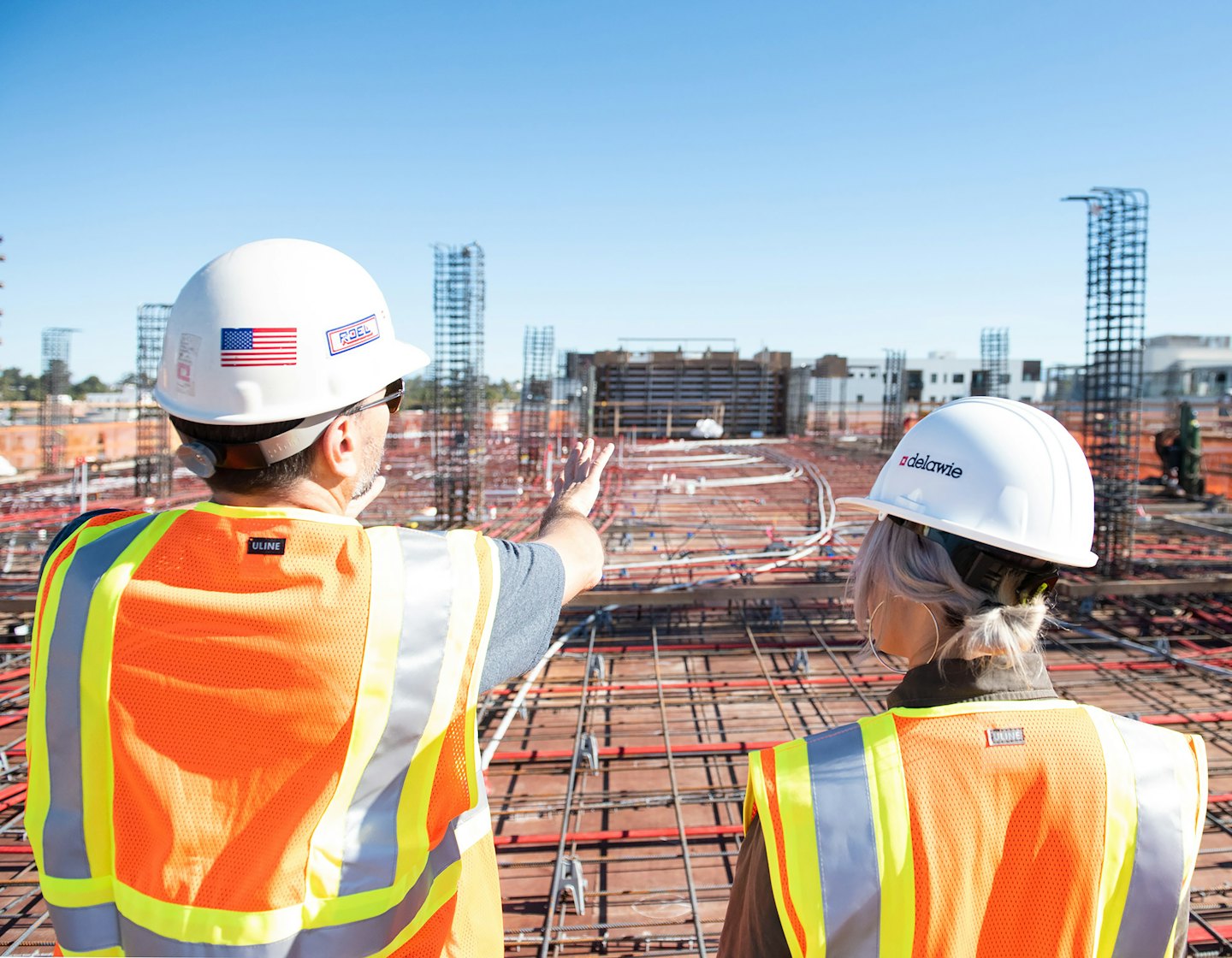 Two construction workers survey an active building site.