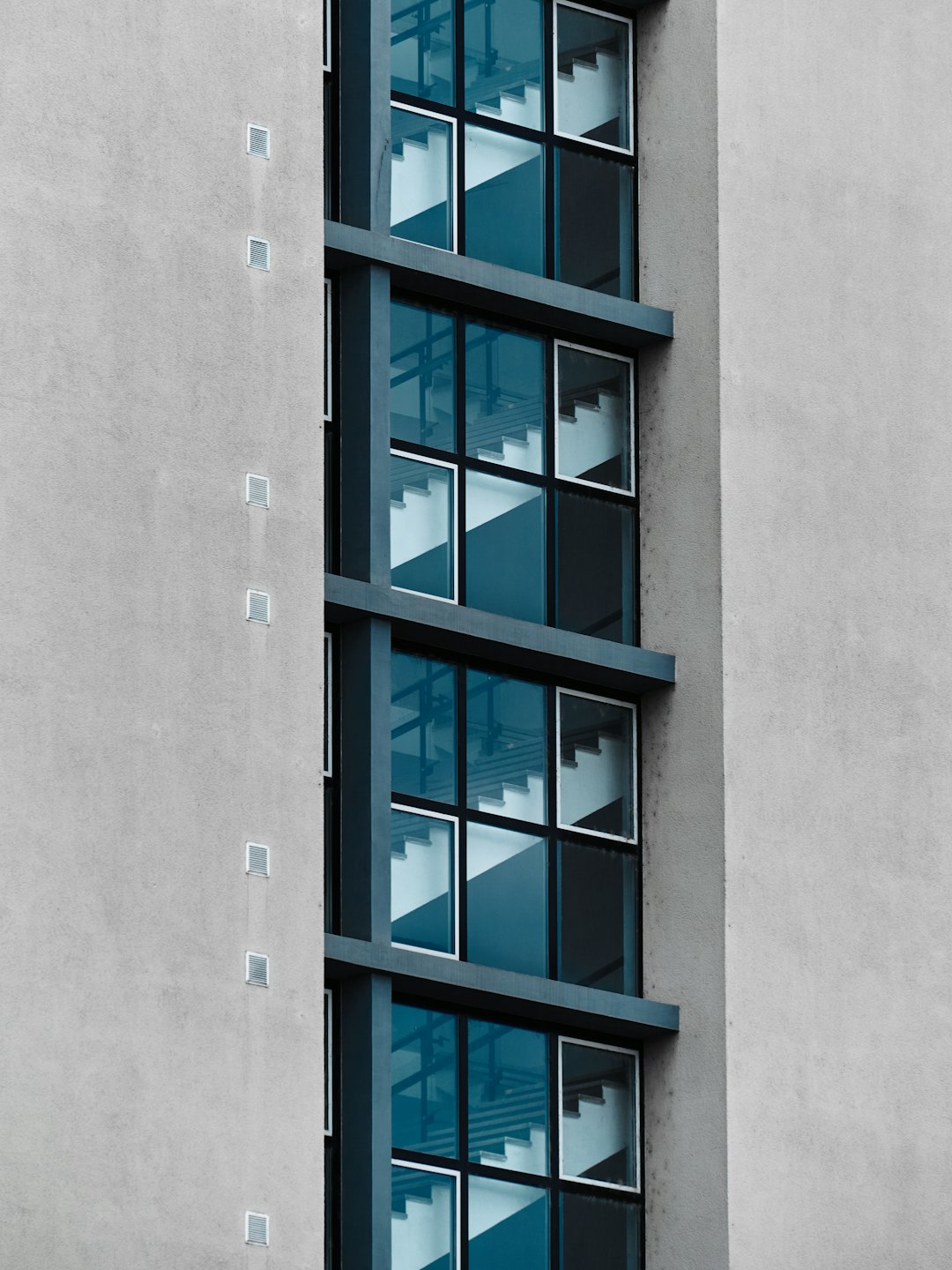 Modern building exterior with concrete wall and rectangular windows.